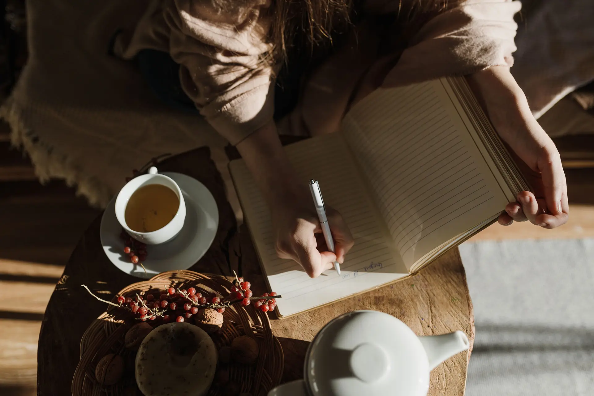Person writing in a notebook with coffee